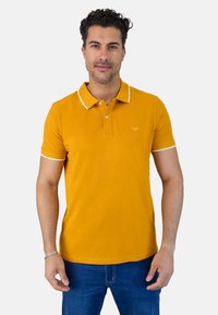 Camisa polo amarilla con collar y ribete de manga blanco; hecha de tela suave; presenta un pequeño logo bordado en el pecho.