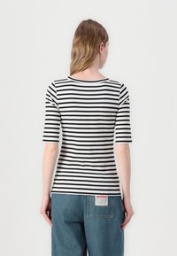 Gestreiftes T-Shirt mit schwarz-weißen horizontalen Streifen, rundem Ausschnitt und kurzen Ärmeln. Material aus Baumwollmischung; Rückseite mit einem Logo-Tag.