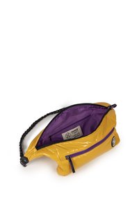 Bolso de charol amarillo con una correa trenzada negra, interior morado, bolsillo con cremallera en la parte frontal y una etiqueta de la marca en el interior.