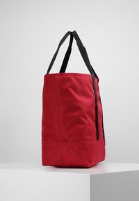 Borsa tote in tessuto rosso con manici neri, forma rettangolare, finitura strutturata e dettagli cuciti alla base per maggiore stabilità.