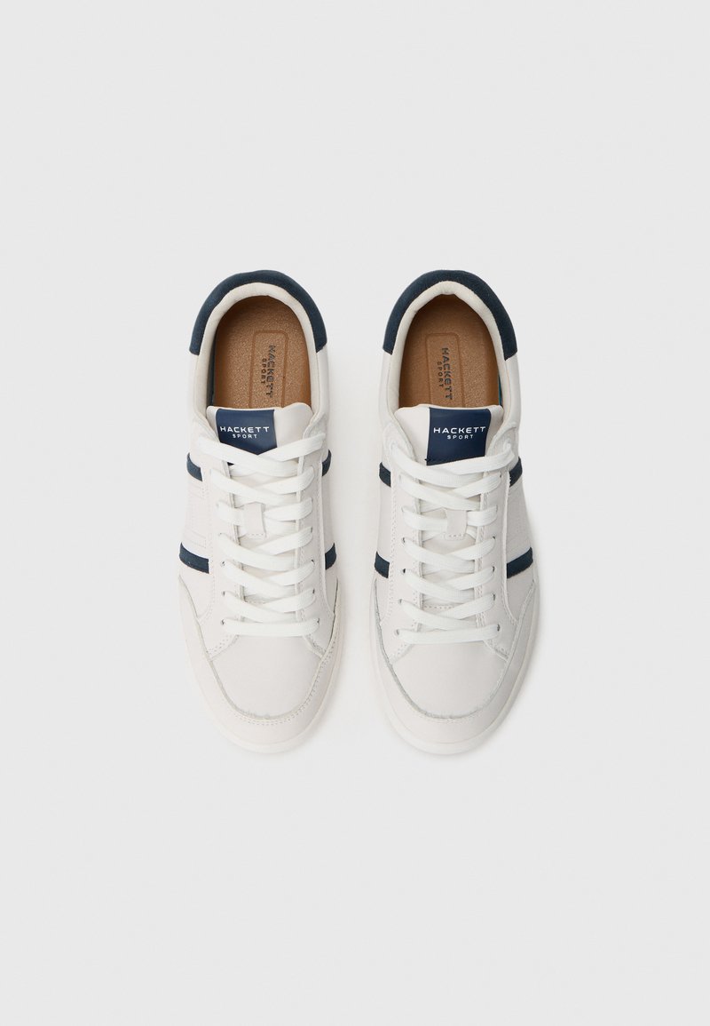 Baskets en cuir blanc avec des accents navy, présentant un design à lacets, une semelle en caoutchouc et une texture lisse. Marque sur la languette.