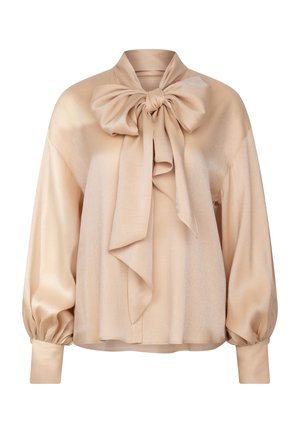 Blusa beige realizzata in un tessuto lucido, presenta un grande fiocco al collo, maniche a palloncino e polsini aderenti. Tessuto liscio con una lucentezza sottile.
