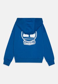 Sudadera de algodón azul con un bolsillo frontal, puños acanalados y un gran logotipo blanco de Timberland en la parte posterior. Cuenta con una capucha con cordones.