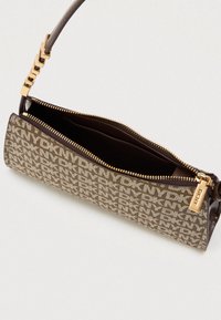 Καφέ τσάντα συμπλέκτη με φερμουάρ που διαθέτει κρέμ μοτίβο, δερμάτινη λωρίδα, χρυσές λεπτομέρειες και ευρύχωρο εσωτερικό, επιδεικνύοντας λεπτομέρειες λογότυπου.