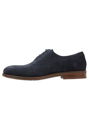 Chaussure Oxford pour homme en daim bleu foncé avec laçage fermé et semelle et talon en cuir marron, vue de profil droit.