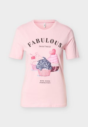 Ανοιχτό ροζ μπλουζάκι με το κείμενο "FABULOUS SWEETNESS" και τρία διακοσμημένα cupcakes, ένα από τα οποία είναι με ασημένιες παγιέτες. Κάτω από το κείμενο υπάρχει η φράση "BITE-SIZED PERFECTION".
