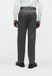 Hallid mustriga püksid tekstuurse viimistlusega, sirge lõikega, vööaugud ja kaks tagataskut, neid täiendab mustade kingade paar.