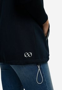 Felpa navy con colletto a coste, tasche laterali, cordino regolabile e logo infinito bianco sull'orlo. Tessuto in cotone morbido.