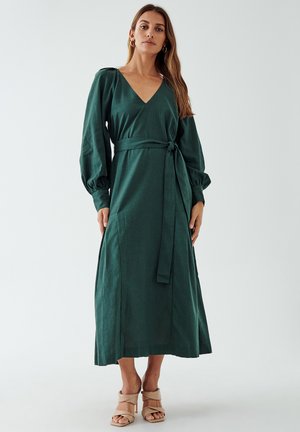 Green linen wrap dress with a v-neck, long voluminous sleeves, and a tied waist sash, featuring a flowing silhouette and ankle-length cut.