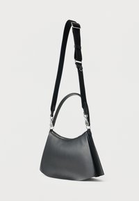 Μαύρη δερμάτινη τσάντα ώμου με ρυθμιζόμενο μαύρο υφασμάτινο λουρί και ασημί μεταλλικά κούμπωμα σε απλό λευκό φόντο.