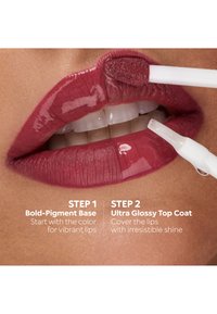 Labbra con rossetto a base pigmentata intensa applicato, applicatore di gloss che aggiunge uno strato superiore ultra lucido per una finitura brillante, mostrando il processo passo dopo passo del colore delle labbra.