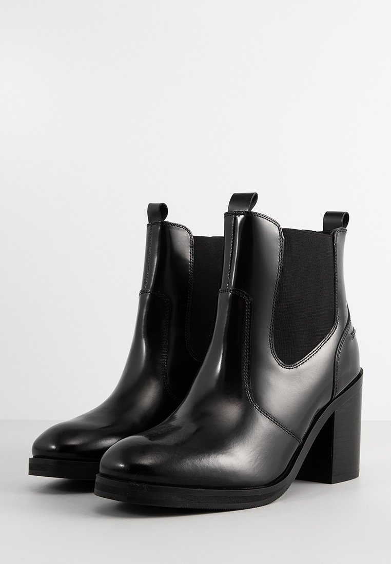 Schwarze Leder-Stiefeletten mit elastischen Seitenpaneelen, runder Zehenpartie und einem 7,5 cm hohen Blockabsatz. Sanfte Textur mit minimaler detaillierter Naht.