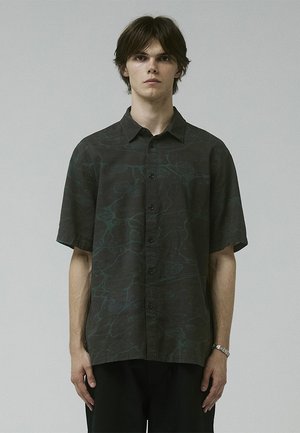Short-sleeve button-up shirt in dark fabric with a fluid, abstract pattern in green. Collared design with black buttons; relaxed fit.