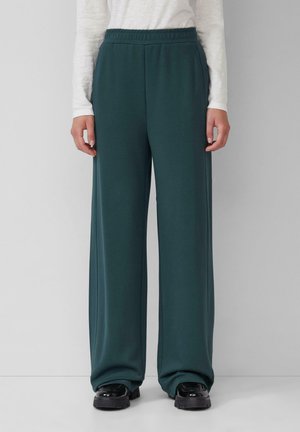 Pantalons larges teal avec une taille élastique, fabriqués à partir d'un tissu doux. Pas de motifs ou d'éléments visibles. Associés à des chaussures noires épaisses.