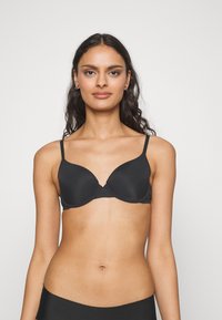 Black padded bra with adjustable straps. Smooth fabric, seamless design, and a subtle U-shaped neckline for an understated look.