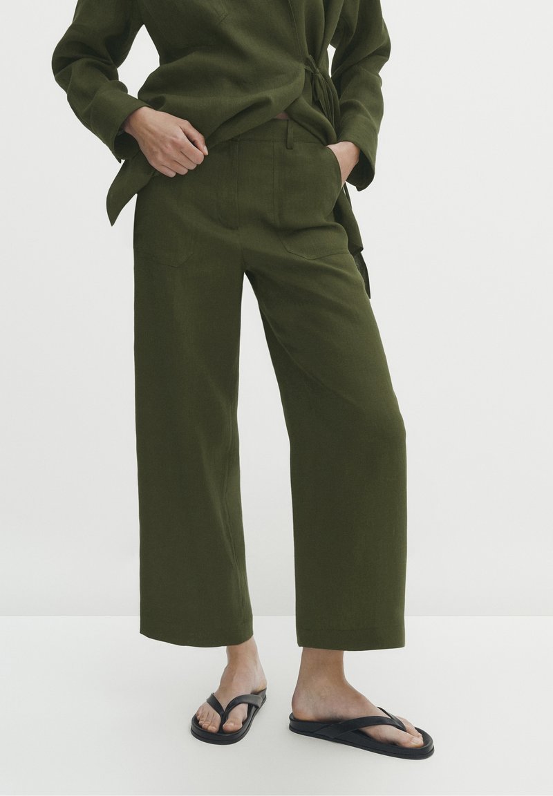 Olive green, szerokie spodnie z kieszeniami z przodu, wykonane z teksturowanej mieszanki lnu, w połączeniu z czarnymi klapkami. Prosty, prosty krój.