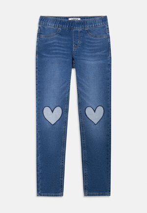 Blå barnjeans med elastisk midja och hjärtformade lappar på båda knäna, visad liggande på en vit bakgrund.