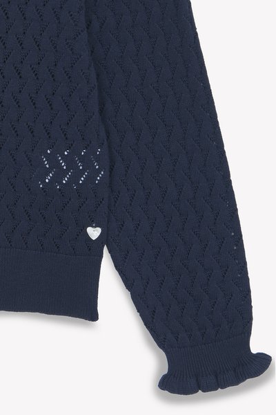 Marinblå stickad tröja med en strukturerad diamantmönster, ribbade ärmslut och dekorativ metall-accent i form av ett hjärta nära fållen.