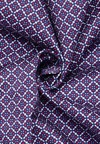 Marineblauwe stof met een geometrisch patroon van rode en witte hexagons, gladde textuur met een lichte glans en subtiele plooien.