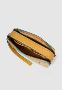 Portafoglio in pelle gialla con dettagli della cerniera blu, caratterizzato da numerosi scomparti, una texture liscia e una tracolla rimovibile per facilitarne il trasporto.