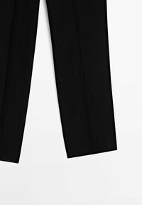 Pantalon noir à jambes droites, posé à plat sur une surface blanche, montrant toute la longueur de la taille à l'ourlet.