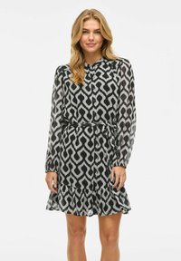 Abito a righe in bianco e nero con maniche lunghe e trasparenti, vita arricciata e orlo ondulato, caratterizzato da un elegante design astratto.