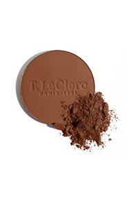 Puder-Bronzer in runder Form, mattes Finish, warme braune Farbe, mit etwas losem Puder, das daneben verstreut ist. Prägierter Markenname sichtbar.