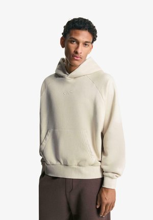Beige hooded sweatshirt with a kangaroo pocket, ribbed cuffs, and hem, featuring a subtle embroidered logo on the chest.