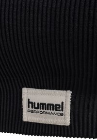 Una diadema deportiva de tela negra con textura de canalé, que cuenta con una etiqueta blanca cosida que muestra "hummel PERFORMANCE" en letras negras.