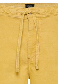 Gule kordfløjlsbukser med snøre foran og et lille sort label ved taljen med teksten "camel active".