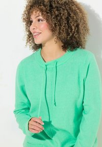 Grön, stickad tröja med rund halsringning, dragsko och framfickor. Den mjuka texturen och de ribbade ärmmuddarna förbättrar designfunktionerna.