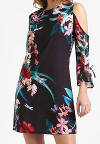 Svart klänning med kall axel-design, blommönster i rosa, rött och grönt, med genomskinliga ärmar och avslappnad passform.