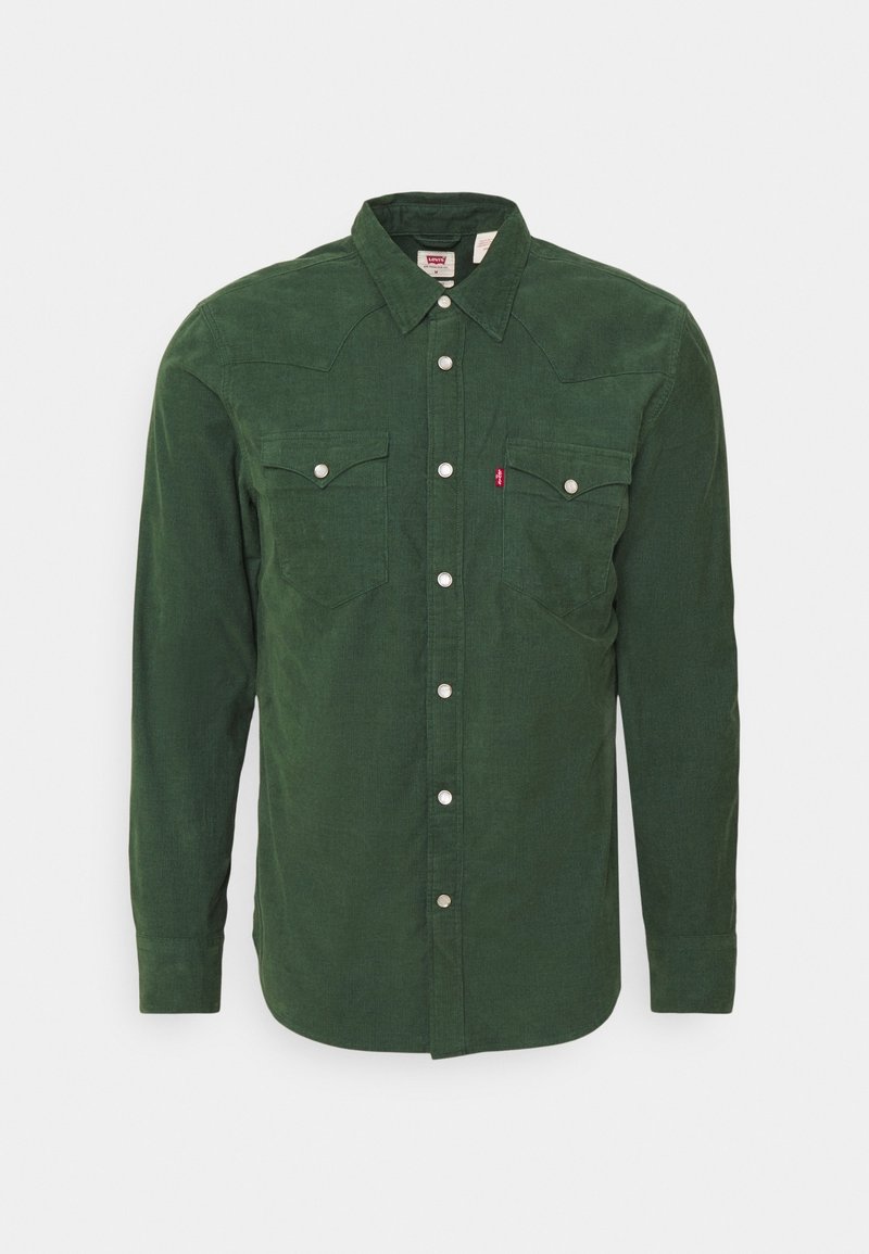 Camicia in velluto a coste verde con maniche lunghe, bottoni a pressione e due tasche sul petto. Presenta un colletto classico e una texture sottile.