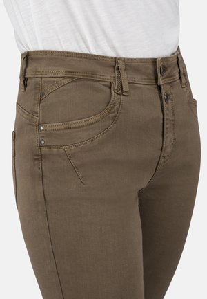 Brown denim jeans with a fitted design, featuring a classic five-pocket style and contrasting stitching. The fabric has a smooth texture.