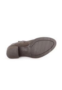 Botte de cheville en suède marron avec un talon bloc, dotée d'une semelle en caoutchouc texturé et de coutures détaillées. Le nom de la marque "Gabor" est visible sur la semelle.