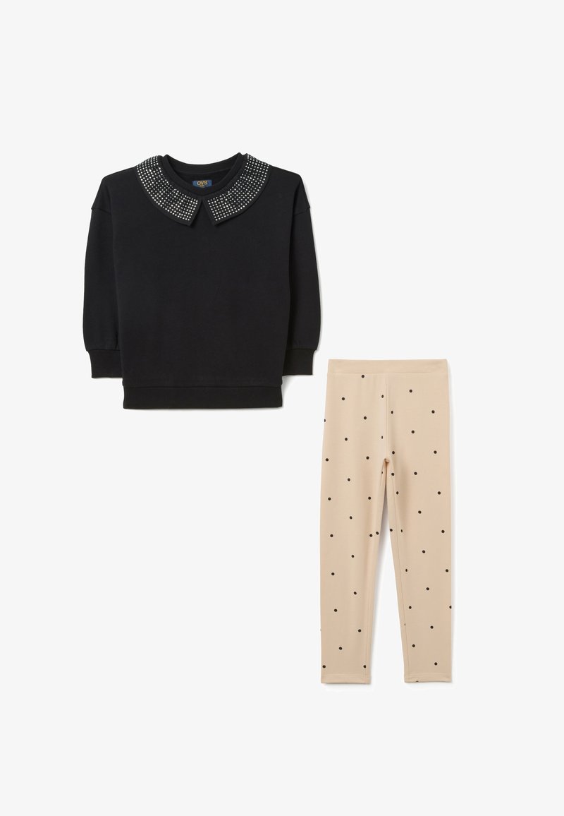 Zwarte sweatshirt met een met studs versierde kraag, gecombineerd met beige legging met zwarte polka dots. Gemaakt van een katoenmix, zachte textuur.