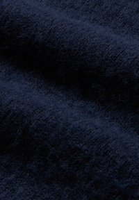 Tmavě navy látka s měkkou, huňatou texturou, která vykazuje bohatou hloubku barvy a mírné variace v tloušťce na vlnících se záhybech.