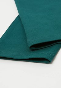 Tessuto di cotone turchese con una trama a coste, piegato all'orlo. Presenta cuciture dritte e pulite lungo i bordi.