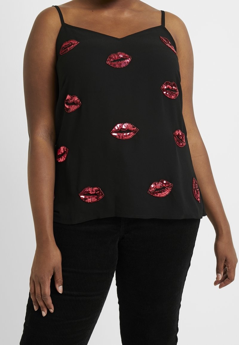 Haut sans manches noir avec fines bretelles, décoré de lèvres rouges brillantes en sequins, porté avec un pantalon noir sur une personne à la peau foncée.