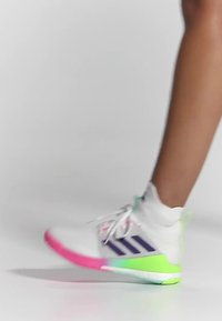 Weißer Turnschuh mit einer rosa und grünen Sohle, lila Streifen und mehrfarbigen Akzenten. Ausgestattet mit einem Obermaterial aus Mesh und Schnürsenkeln.