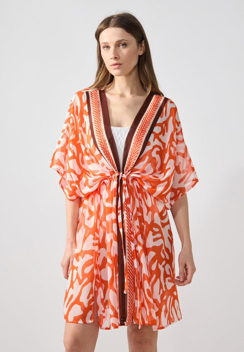 Kimono in stampa arancione e bianco, realizzato in tessuto leggero, con scollo a V e rifiniture marroni, vita cinchata, maniche ampie e design fluido.