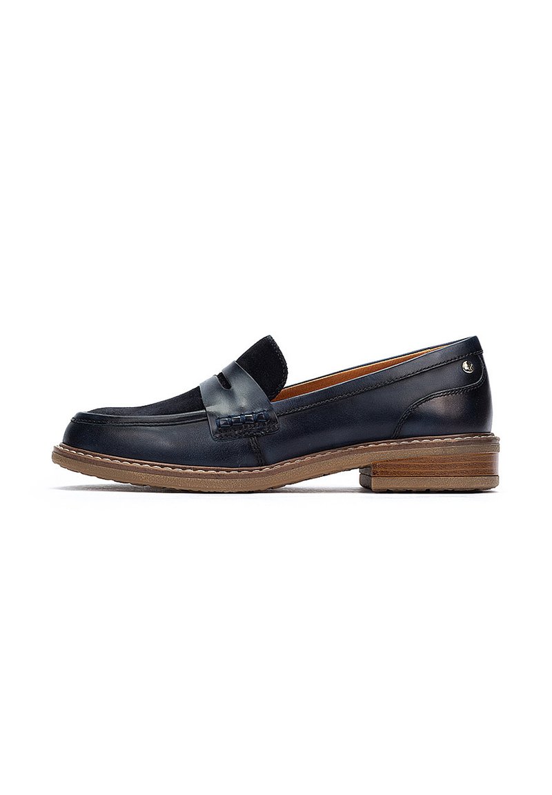 Mocasines de cuero azul marino con un acento de ante, suela plana marrón y costuras decorativas en el empeine, con un ligero tacón.