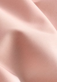 Svijetloružičasta tkanina glatke, mat teksture koja prikazuje fine detalje tkanja, suptilni sjaj i nježne nabore. Prikladna za razne primjene.