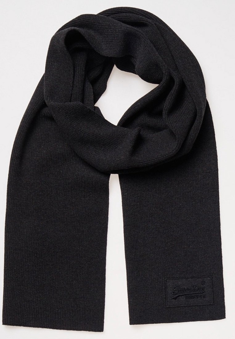 Écharpe noire tricotée avec texture côtelée et une petite étiquette rectangulaire en tissu sur une extrémité, étalée à plat avec une boucle lâche en haut.