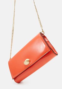 Bolso bandolera de charol naranja con cierre de botón a presión dorado, forma rectangular elegante y correa de cadena.