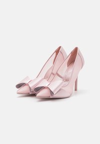 Escarpins en satin rose avec une insertion transparente, bout pointu et un nœud surdimensionné avec des accents pailletés à l'avant.