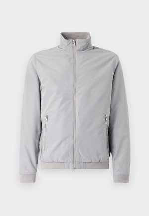 Veste gris clair avec col montant, fermeture éclair et deux poches latérales zippées. Dotée de poignets et d'un ourlet côtelés, texture lisse.