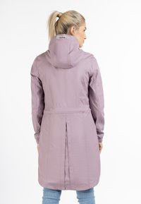 Jachetă lungă de lavandă, confecționată dintr-un material fin, dotată cu glugă, detalii cu șnur, plisuri laterale și mansete ajustate.