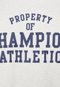 Světlé šedé mikiny s tučným námořnickým textem "MAJITELEM CHAMPION ATHLETIC." Má klasický design s kulatým výstřihem a je vyrobena z bavlny.