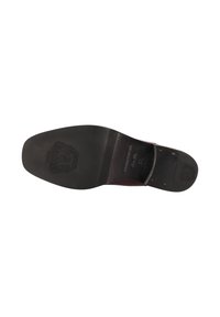 Suela de zapato de cuero con un acabado negro suave, que presenta un logotipo detallado en relieve y una textura estriada cerca del talón para mayor agarre.